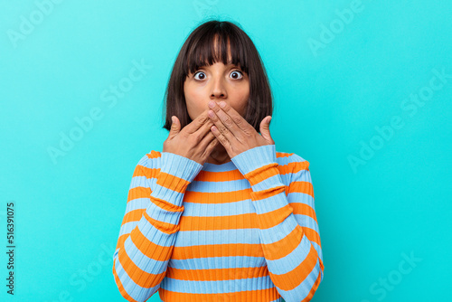 Young mixed race woman isolated on blue background shocked covering mouth with hands.