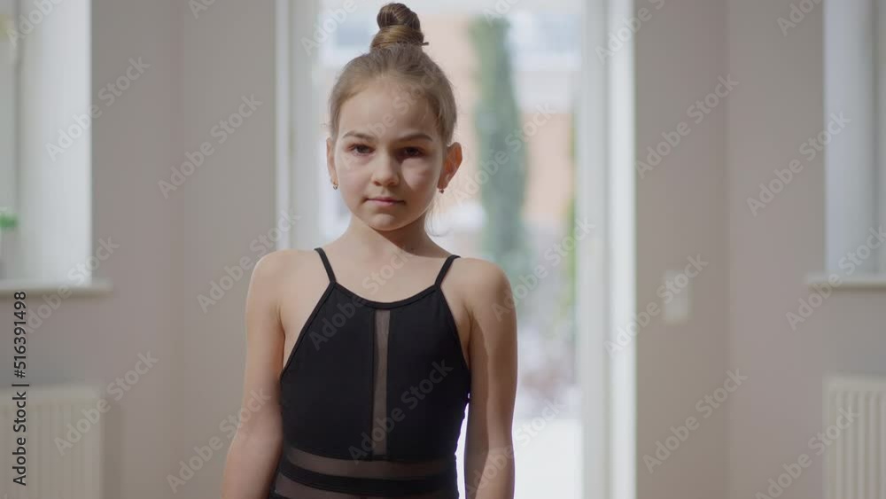 Medium shot portrait of confident teen gymnast looking at camera standing indoors. Front view of Caucasian talented motivated girl posing in slow motion Medium shot portrait of confident teen gymnast looking at camera standing indoors. Front view of Caucasian talented motivated girl posing in slow motion