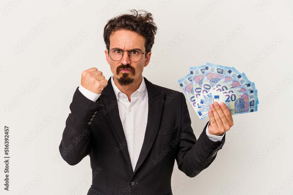 Young caucasian man holding banknotes isolated on white background showing fist to camera, aggressive facial expression. Young caucasian man holding banknotes isolated on white background showing fist to camera, aggressive facial expression.