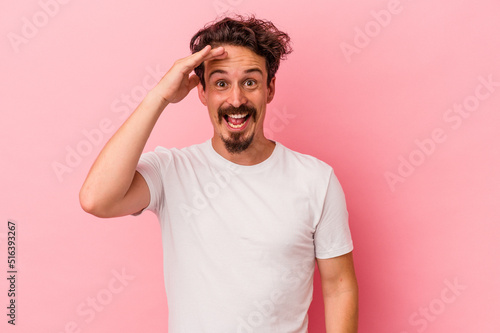 Young caucasian man isolated on pink background shouts loud, keeps eyes opened and hands tense.