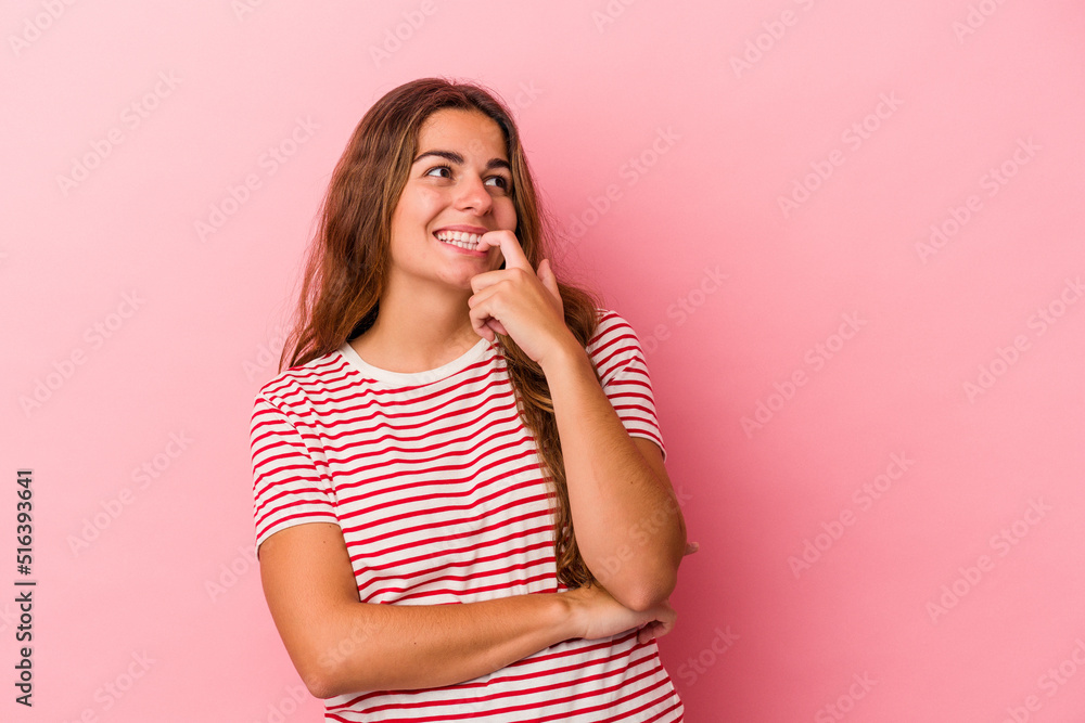 Young caucasian woman isolated on pink background relaxed thinking about something looking at a copy space. Young caucasian woman isolated on pink background relaxed thinking about something looking at a copy space.