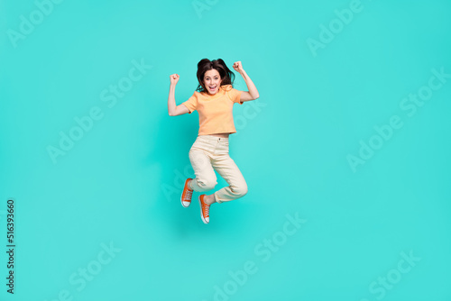 Full size portrait of astonished satisfied lady jump raise fists scream yes isolated on turquoise color background