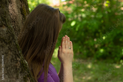 Canvas Print Faithful married Christian woman praying to God Jesus Christ with hands in a prayer position and head bowed down alone in nature