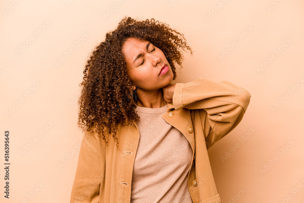 Young African American woman isolated on beige background massaging elbow, suffering after a bad movement. Young African American woman isolated on beige background massaging elbow, suffering after a bad movement.