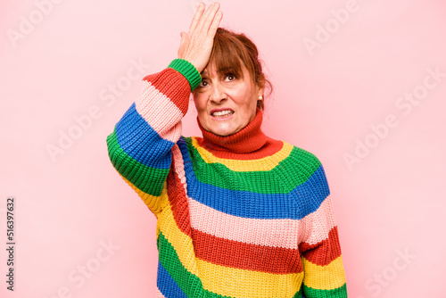 Middle age caucasian woman isolated on pink background forgetting something, slapping forehead with palm and closing eyes.