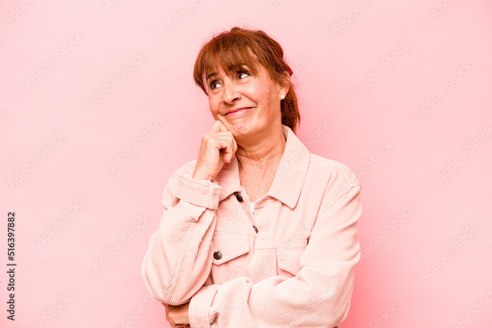 Middle age caucasian woman isolated on pink background thinking and looking up, being reflective, contemplating, having a fantasy.