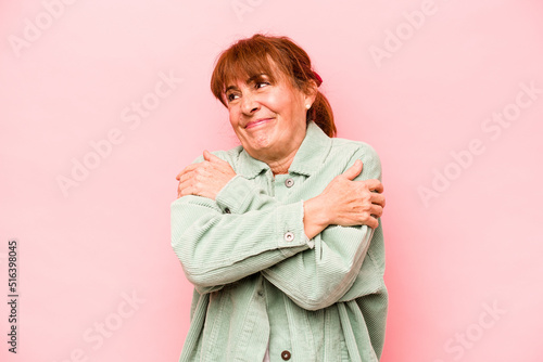 Middle age caucasian woman isolated on pink background hugs, smiling carefree and happy. © Asier