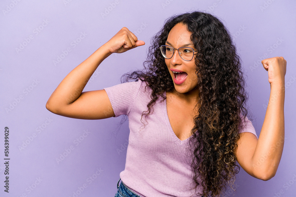 Young hispanic woman isolated on purple background raising fist after a victory, winner concept. Young hispanic woman isolated on purple background raising fist after a victory, winner concept.