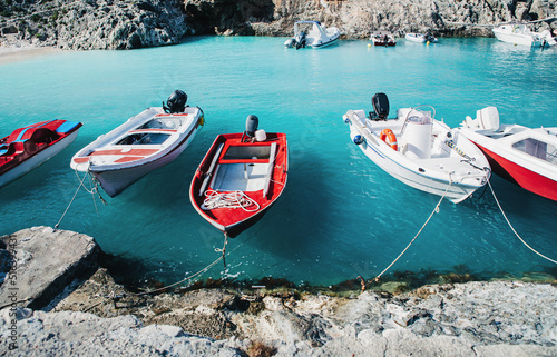 Turquoise azure blue sea water and bright red and white speed boats at anchor. Seaside. Touristic destination. Boat trip. Greece island bay or lagoon