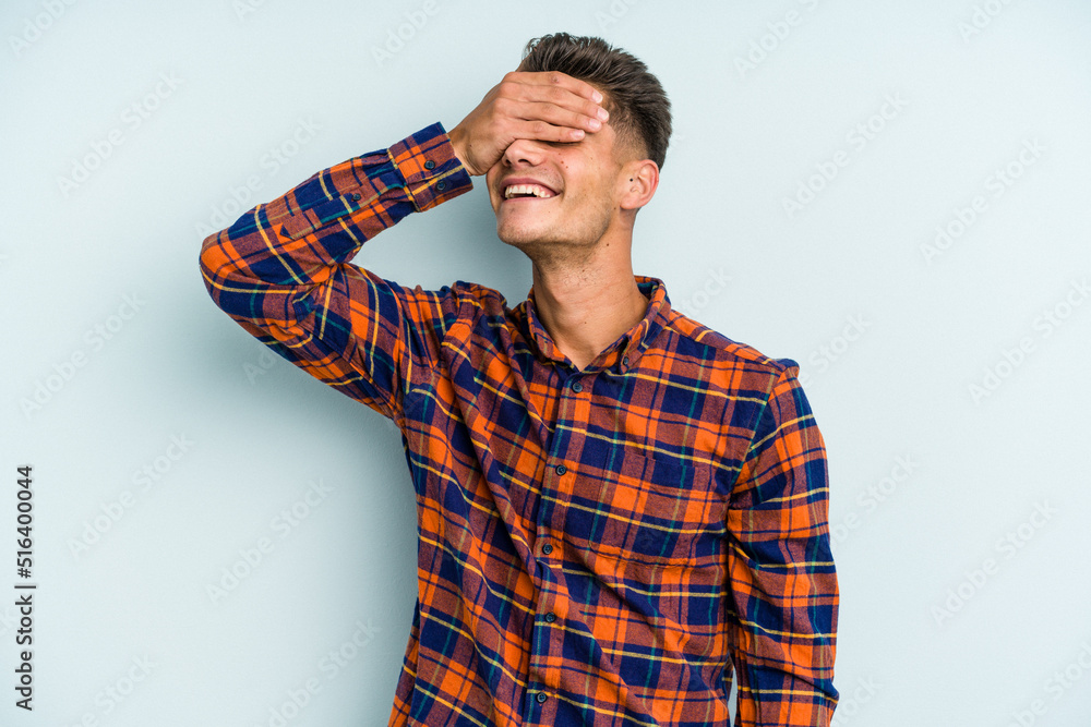 Young caucasian man isolated on blue background covers eyes with hands, smiles broadly waiting for a surprise. Young caucasian man isolated on blue background covers eyes with hands, smiles broadly waiting for a surprise.