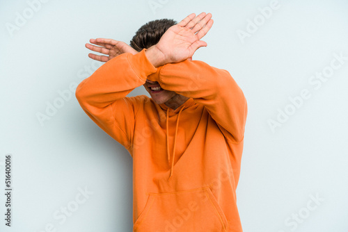 Young caucasian man isolated on blue background keeping two arms crossed, denial concept.