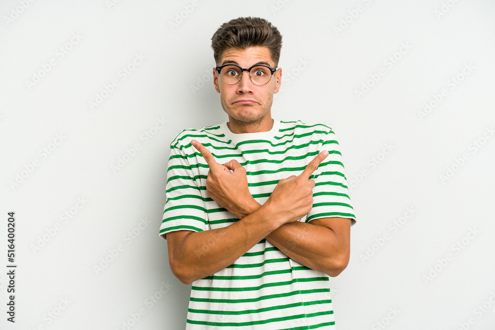 Young caucasian man isolated on white background points sideways, is trying to choose between two options. Young caucasian man isolated on white background points sideways, is trying to choose between two options.