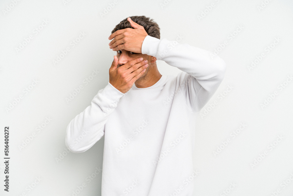 Young caucasian man isolated on white background blink at the camera through fingers, embarrassed covering face. Young caucasian man isolated on white background blink at the camera through fingers, embarrassed covering face.