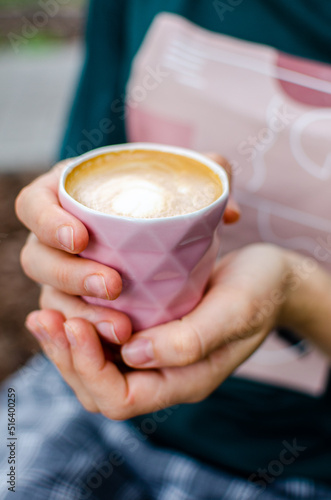 Female hands holding a cup of fresh flat white coffee drink.