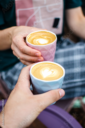 Female and male hands holding a cup of fresh flat white coffee drink.