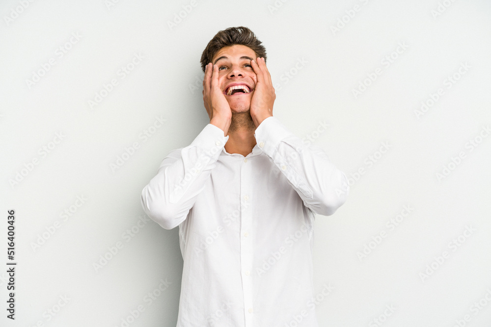 Young caucasian man isolated on white background laughs joyfully keeping hands on head. Happiness concept. Young caucasian man isolated on white background laughs joyfully keeping hands on head. Happiness concept.