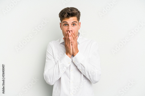 Young caucasian man isolated on white background covering mouth with hands looking worried.