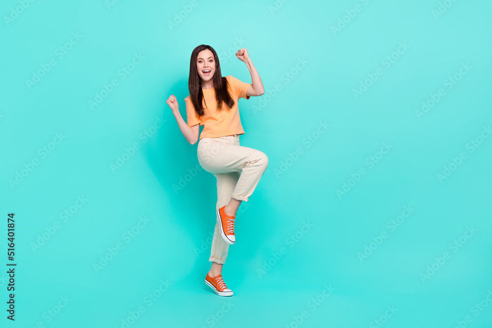Full size photo of delighted satisfied lady raise fists up accomplishment isolated on turquoise color background Full size photo of delighted satisfied lady raise fists up accomplishment isolated on turquoise color background
