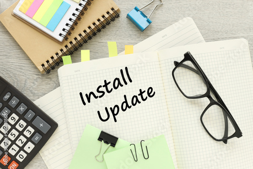 Install updates button . text on a notepad near glasses and stickers.