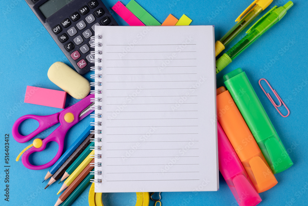 Image of various office supplies, pens and notebook on blue background Image of various office supplies, pens and notebook on blue background