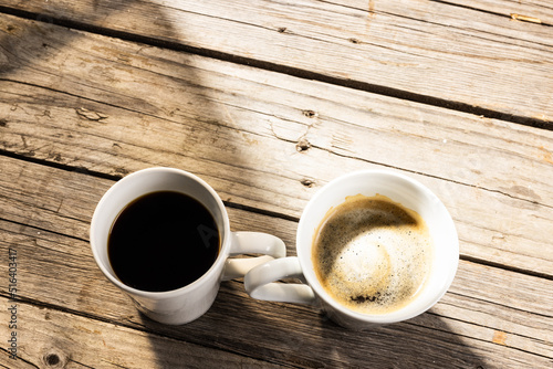Image of two white cup of black coffee on wooden background