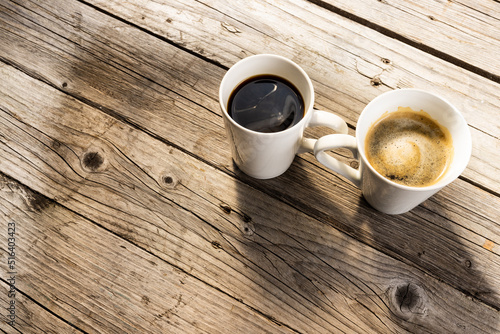 Image of two white cup of black coffee on wooden background