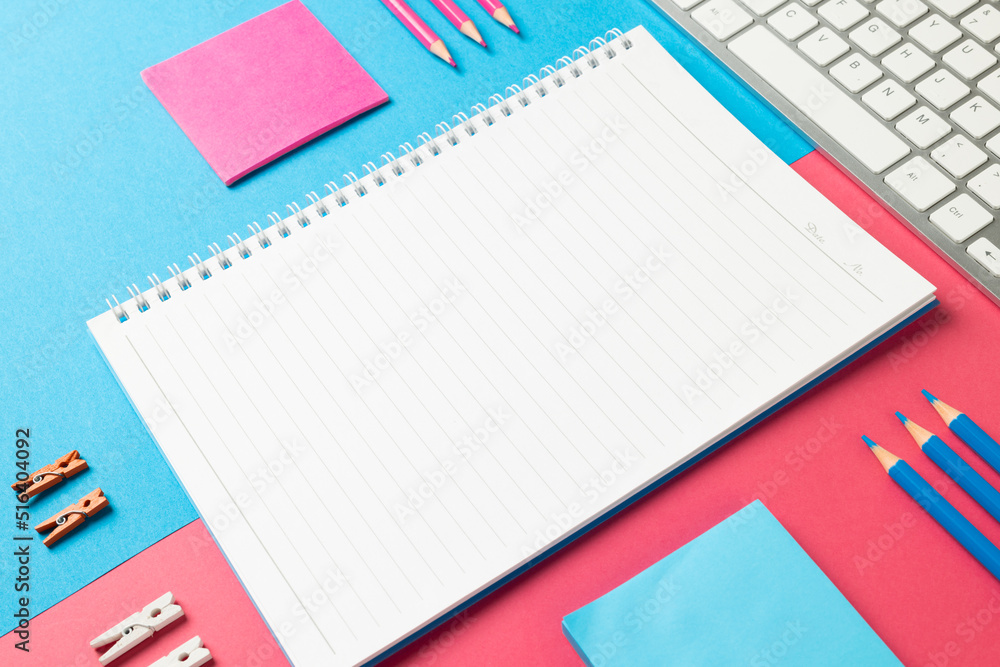 Composition of notebook with copy space, laptop and school equipment on blue and pink surface Composition of notebook with copy space, laptop and school equipment on blue and pink surface