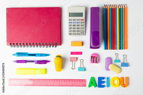 Composition of colorful school equipment with notebook and calculator on white surface