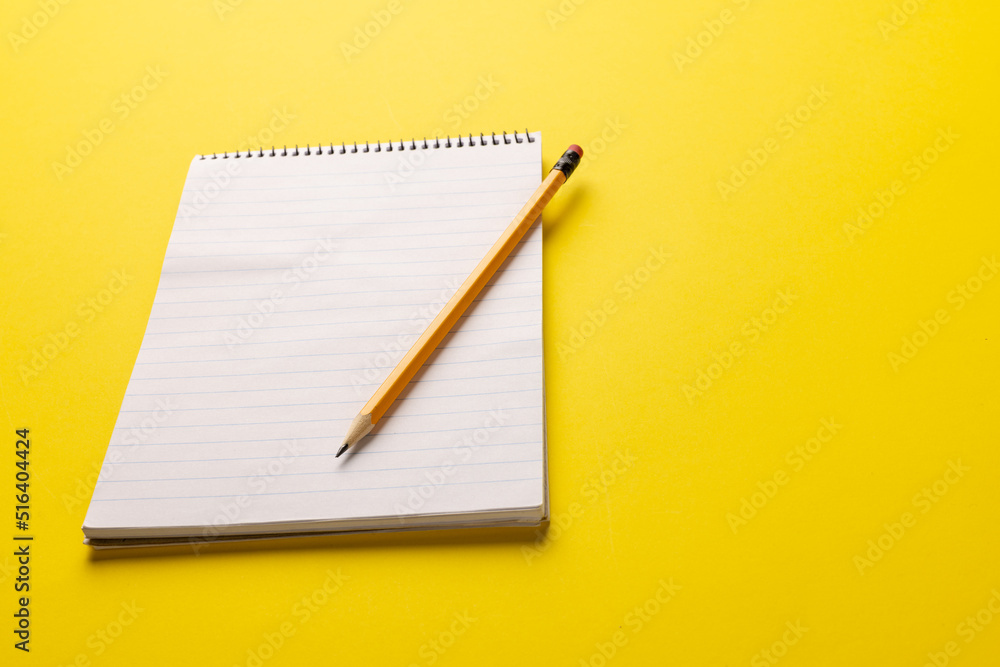 Image of notebook with copy space and pencil on yellow surface Image of notebook with copy space and pencil on yellow surface