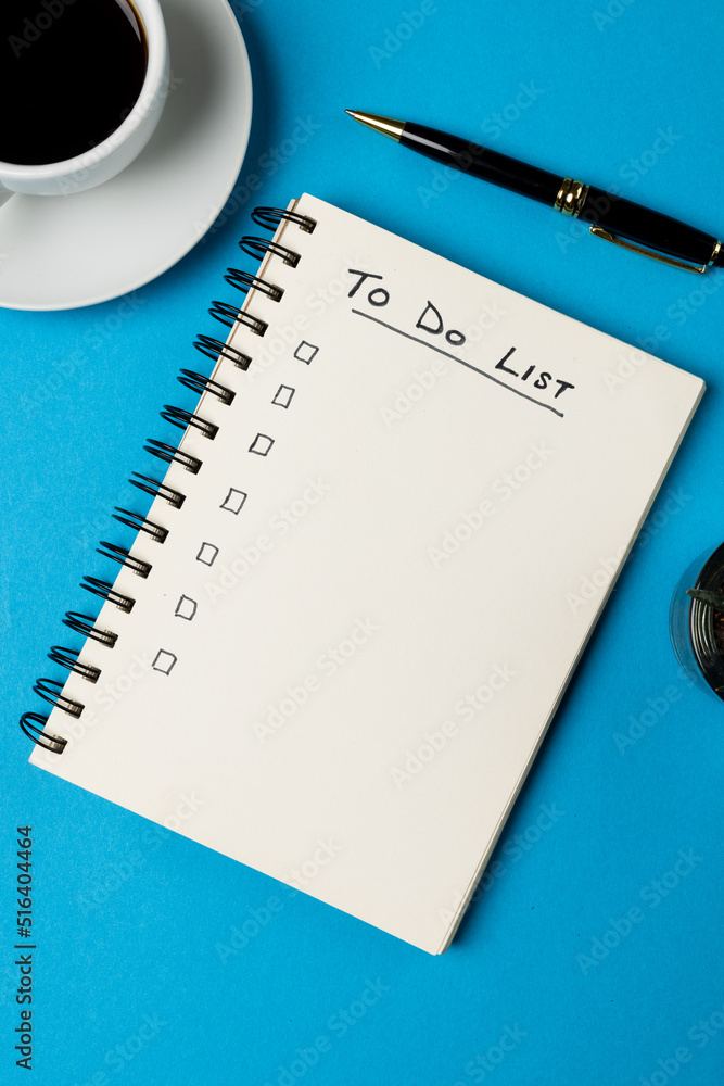 Vertical image of notebook with to do list and copy space, coffee and pen on blue surface Vertical image of notebook with to do list and copy space, coffee and pen on blue surface