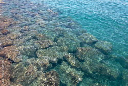 Transparent aquamarine sea water surface with stones underwater