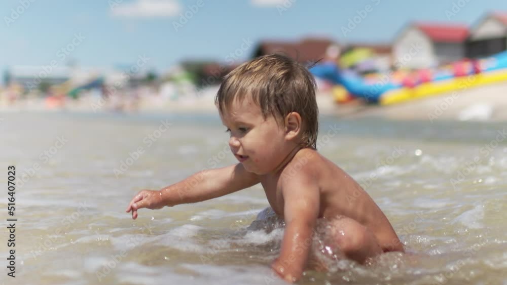 Kid collects shells and pebbles in the sea on a sandy bottom under the summer sun on a vacation Kid collects shells and pebbles in the sea on a sandy bottom under the summer sun on a vacation