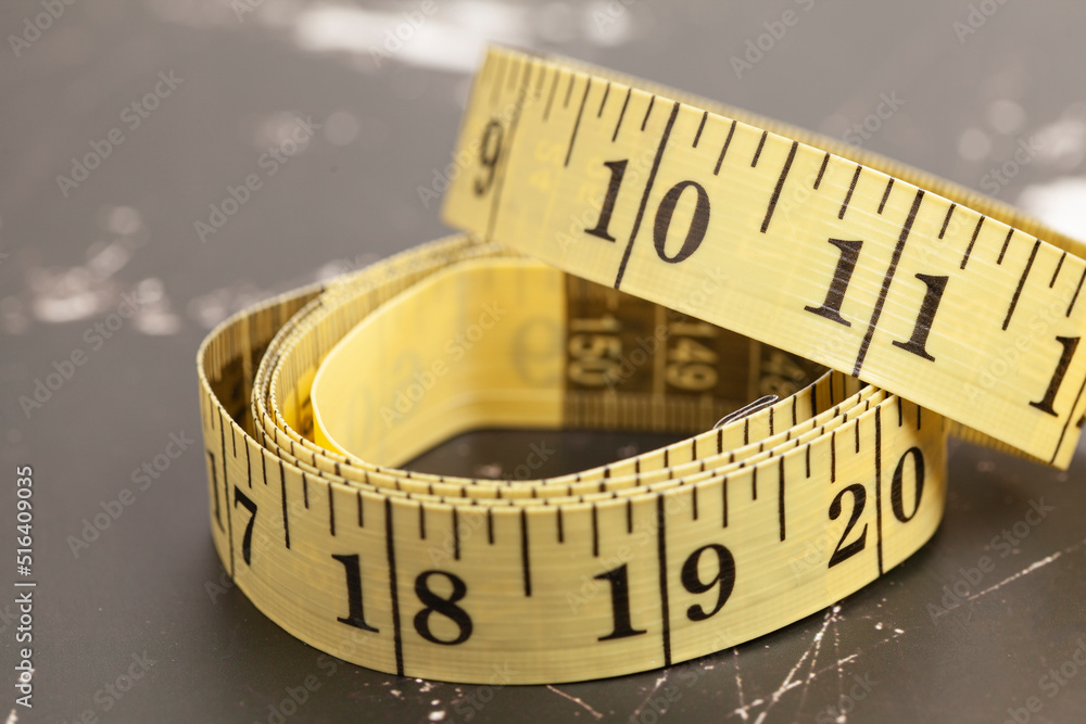 Yellow measuring tape on a marble background. Yellow measuring tape on a marble background.