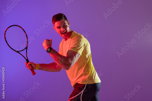 Happy caucasian male tennis player with tennis racket over neon pink lighting © vectorfusionart