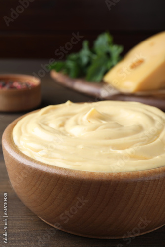 Tasty cheese sauce in bowl on wooden table, closeup