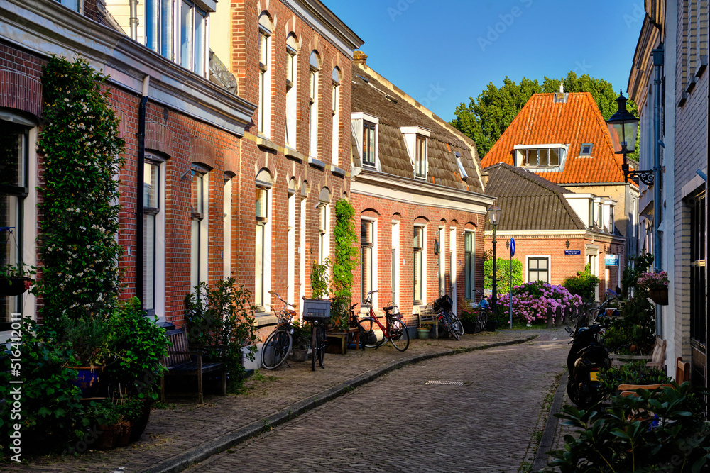 Weesp, Netherlands - July 05. 2022.  An empty side street in evening sunshine with clear blue sky.
