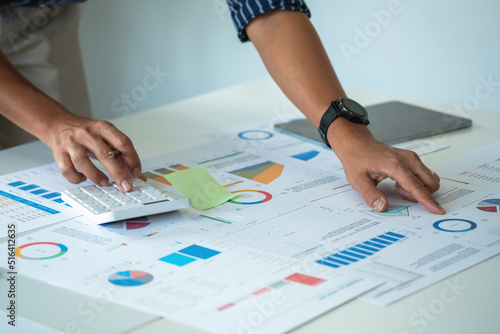 Business men use calculators and graph analysis laptops to plan marketing strategies and make profitable investments in the company.