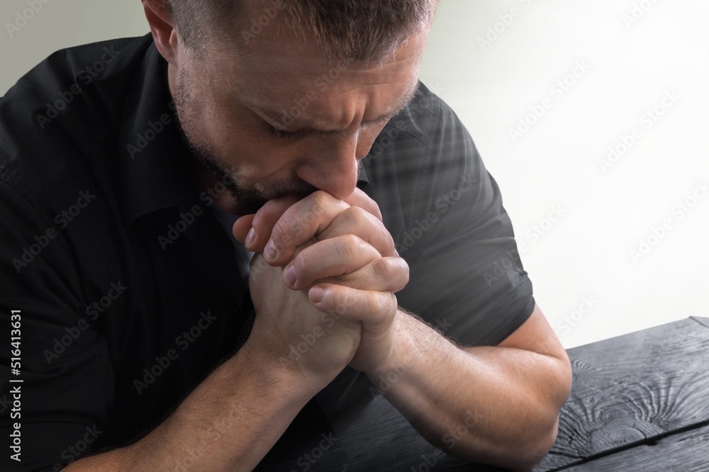 A faithful young male hands in prayer gesture sitting alone pray and hope for good luck, success, forgiveness. Power of religion, belief, god faith, worship concept ideas. A faithful young male hands in prayer gesture sitting alone pray and hope for good luck, success, forgiveness. Power of religion, belief, god faith, worship concept ideas.