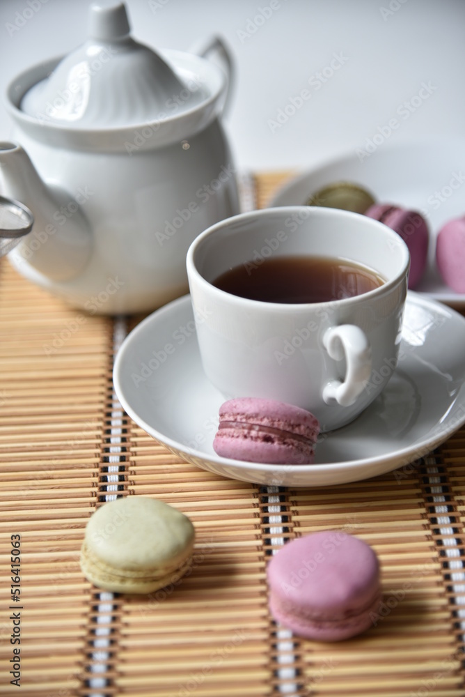 Porcelain teapot with a cup of tea and macaroons
