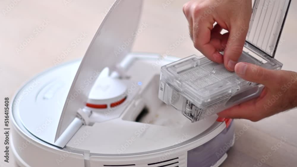 Man cleaning hair and dust on a white vacuum robot at home, close up Man cleaning hair and dust on a white vacuum robot at home, close up