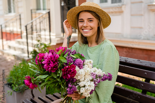 beautiful young woman in summer style outfit smiling happy walking with flowers in city street