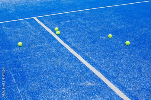selective focus, several paddle tennis balls on a blue artificial grass paddle tennis court © Vic