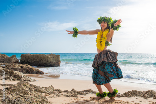 Hula dancer dancing Hawaiian dance on the beach in tropical outfit. Smiling woman dancing a hawaii dance. Person with Polynesian and Tahitian attire.