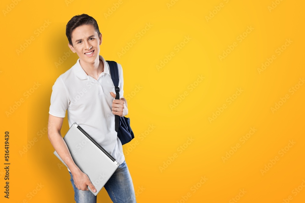 Cheerful young man holding laptop standing, student or freelancer carrying laptop computer. Cheerful young man holding laptop standing, student or freelancer carrying laptop computer.