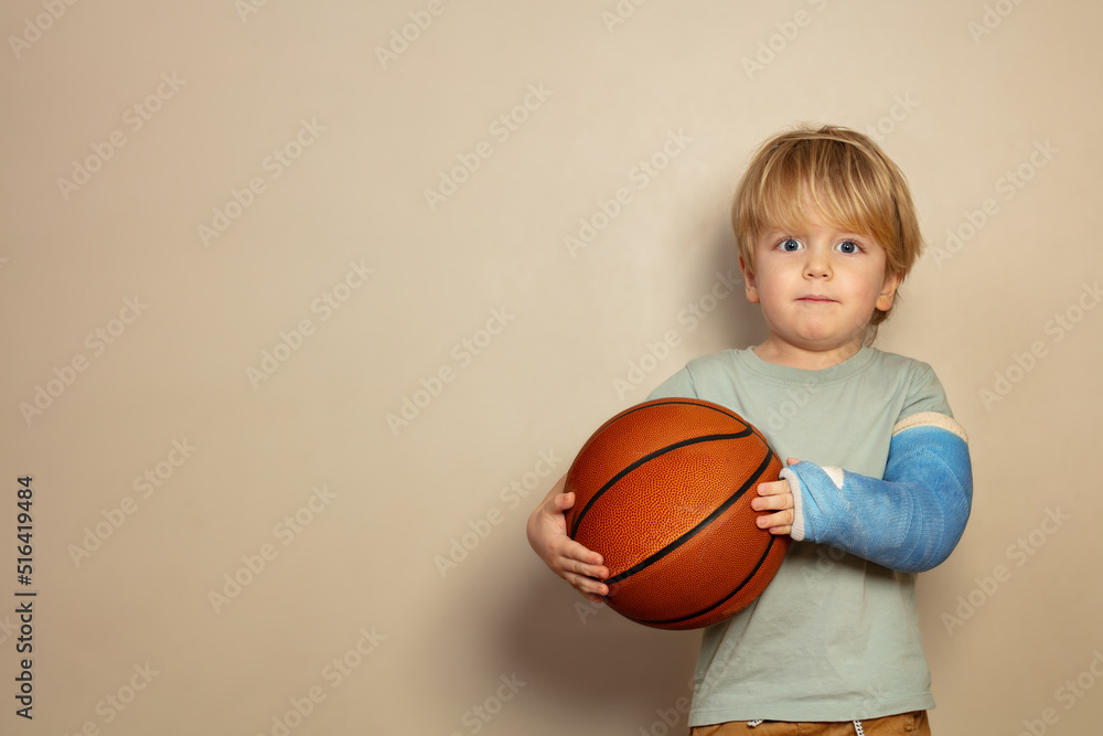 Child hold basketball ball with broken hand in plaster cast Child hold basketball ball with broken hand in plaster cast