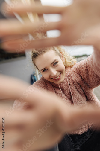 Young teenage girl looking at camera through her hands laughing