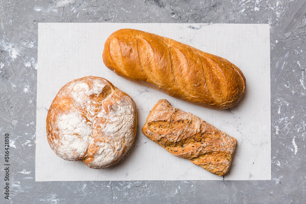 Assortment of freshly baked bread with napkin on rustic table top view. Healthy unleavened bread. French bread Assortment of freshly baked bread with napkin on rustic table top view. Healthy unleavened bread. French bread