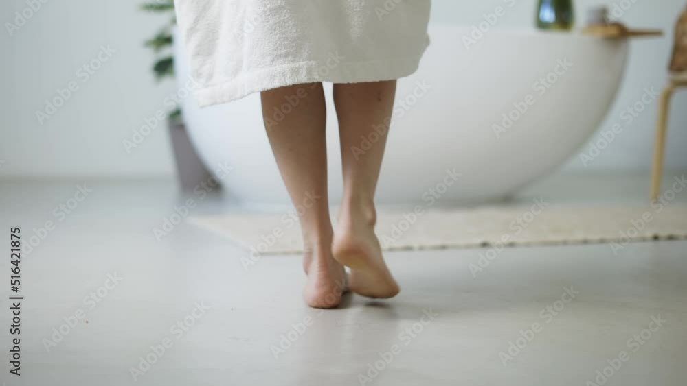 Elegant woman walk to the bath, then she takes off her white bathrobe and climbs into the bathroom