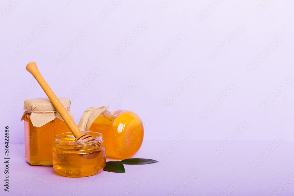 Honey in jar with leaves and honey dipper on colored background top view with copy text Honey in jar with leaves and honey dipper on colored background top view with copy text