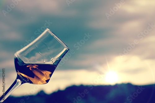 Glass of sweet wine with a Sunset Tuscan wine yard as background .